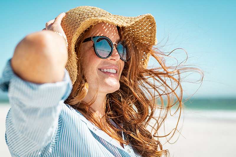 Woman with beach hat and sunglasses at the beach