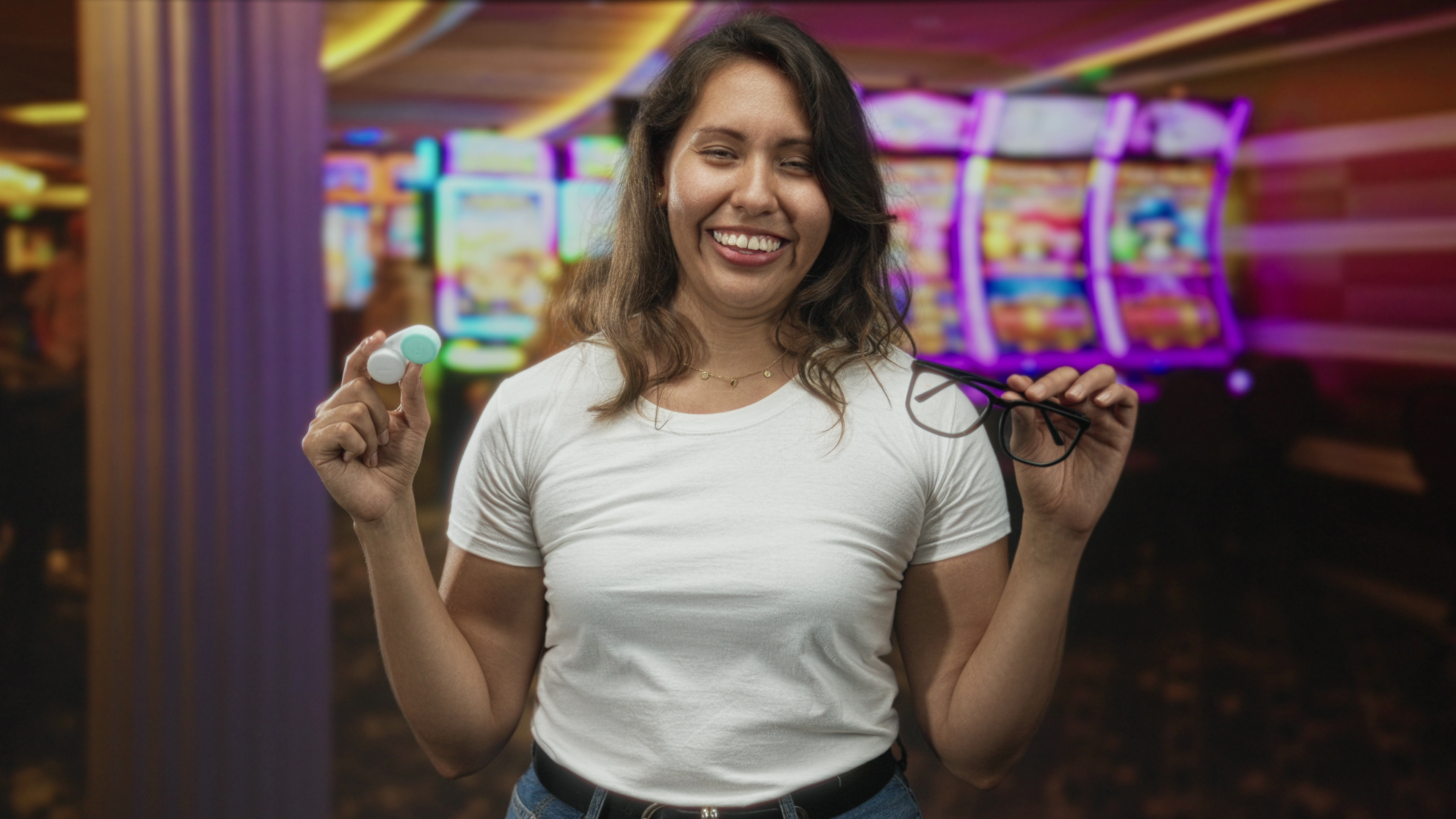 Woman holding glasses and contact lens case in casino building with eyes closed and smiling