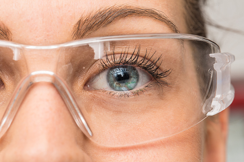 Close up of a woman wearing protective eyewear in the workplace.