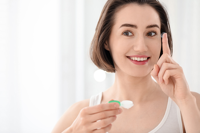 Woman holding contact lenses and case.