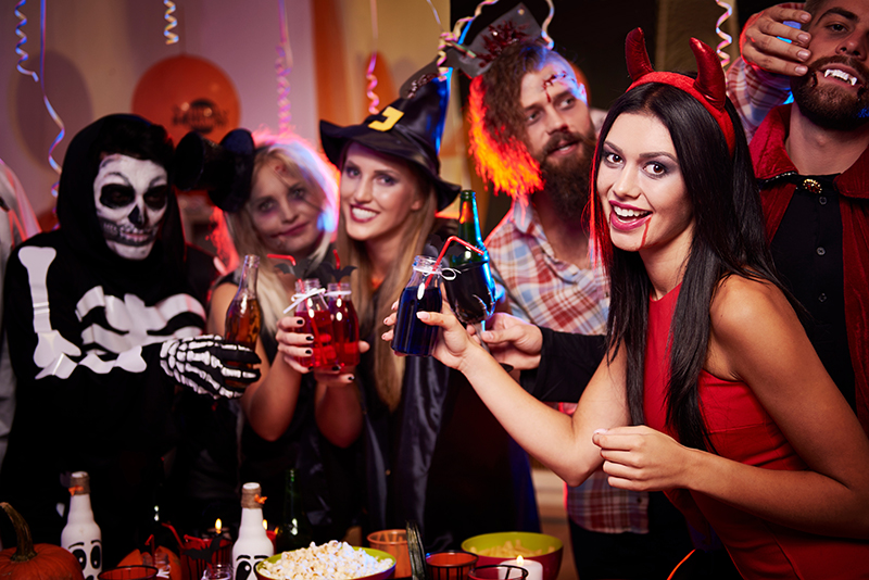 Group of people dressed in various Halloween costumes enjoying a festive Halloween party atmosphere
