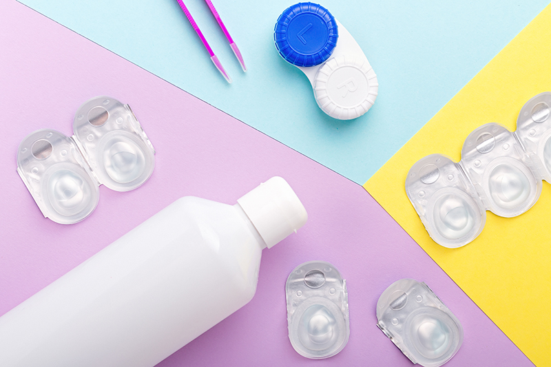 An image of contact lens cases, blister packs, a tweezer and bottle.