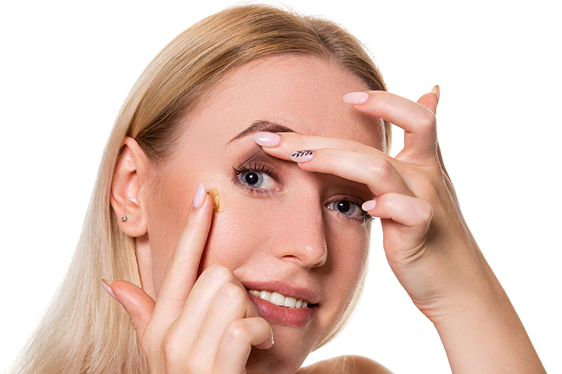 An image of a woman putting in contact lenses
