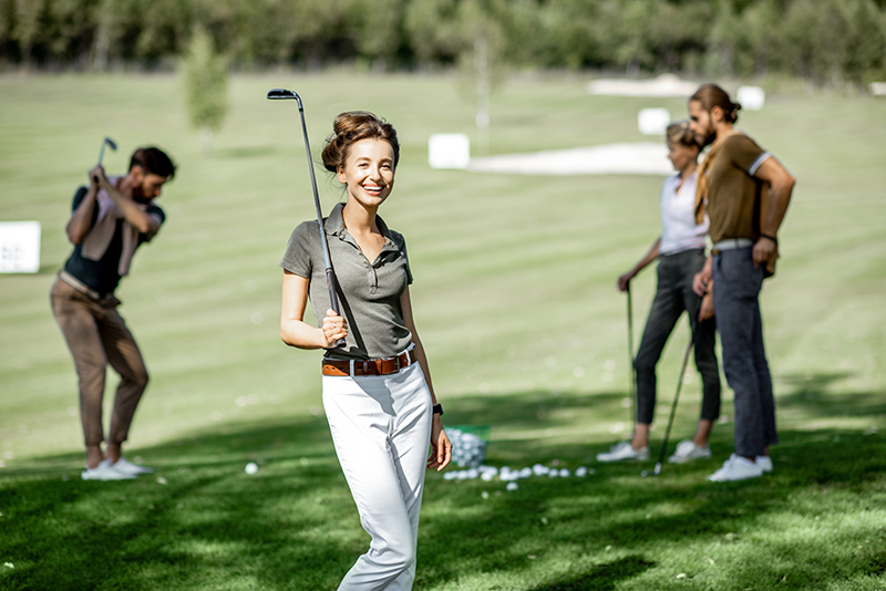 Women enjoying a game of golf on a course, surrounded by friends